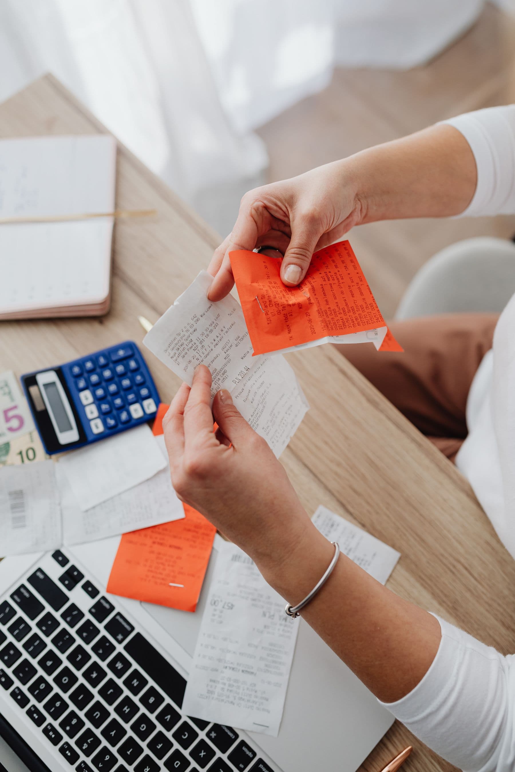 Hands sorting through paper receipts beside a calculator